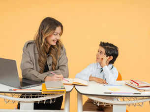 A teacher and student smile as they engage in a learning activity in a classroom.