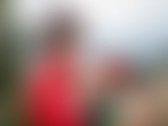 Sid view of serious adult ethnic lady in traditional outfit and hat standing in mountainous countryside with brown lama