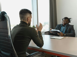Two men in a job interview setting in a modern office with large windows.