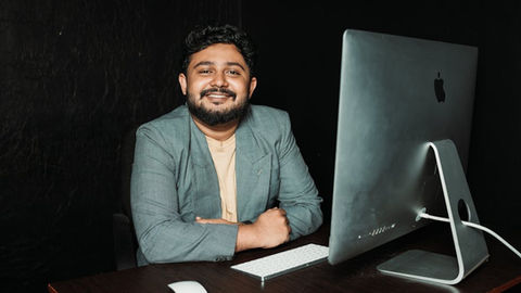 Confident businessman sitting at desk, working on computer in modern office.