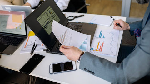 Professionals analyzing charts and graphs on laptops.