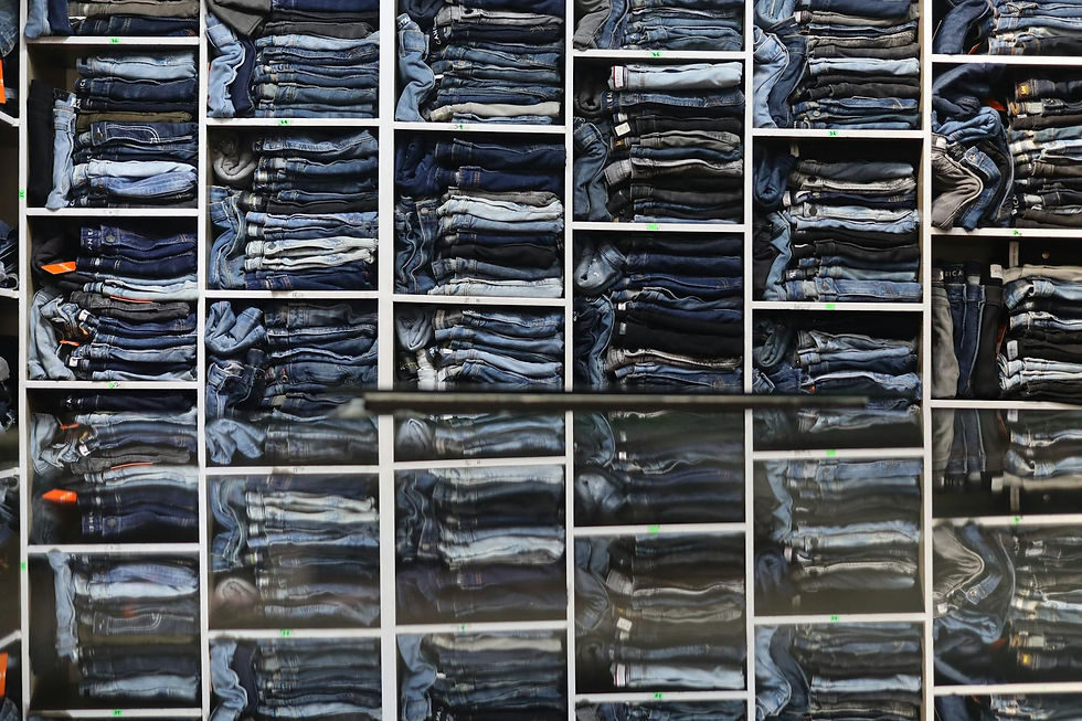 Organized display of folded jeans on shelves in a retail clothing store.