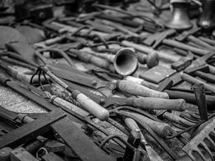 Black and white photo of a stack of vintage carpentry tools showcasing rustic charm and history.