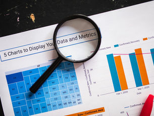 Close-up of business charts with magnifying glass highlighting data insights.