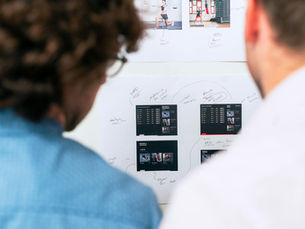Two business professionals brainstorming and planning software development with a whiteboard in an office.