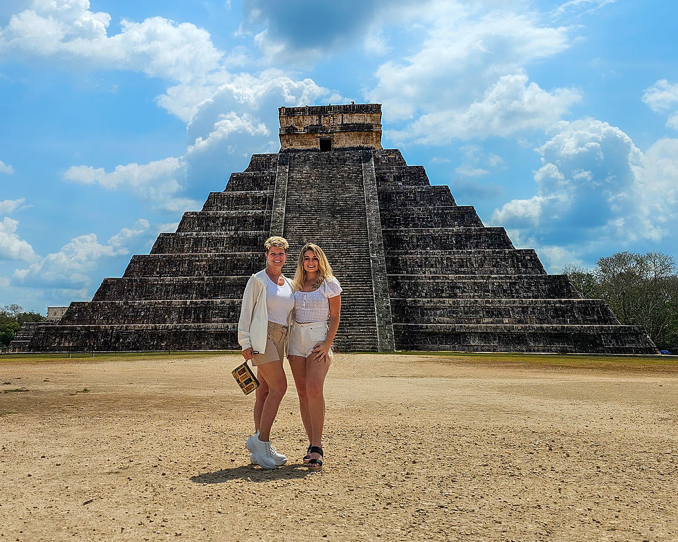 Travel blogger JJ Royer and her daughter pose in front of El Castillo at Chichen Itza in Mexico