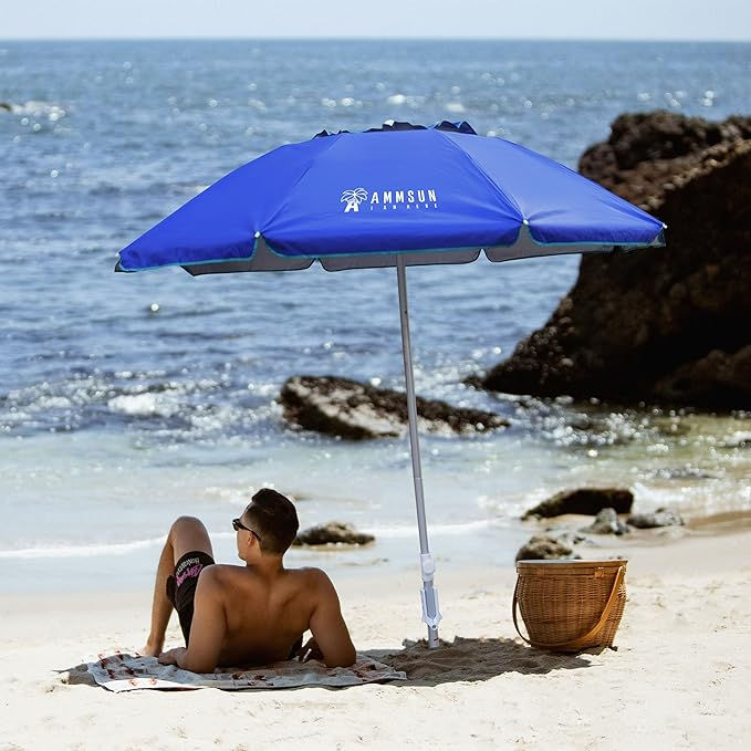 A man lounges under a compact beach umbrella at the beach