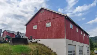 Slitt rød trefasade på landbruksbygg i Maura før maling.