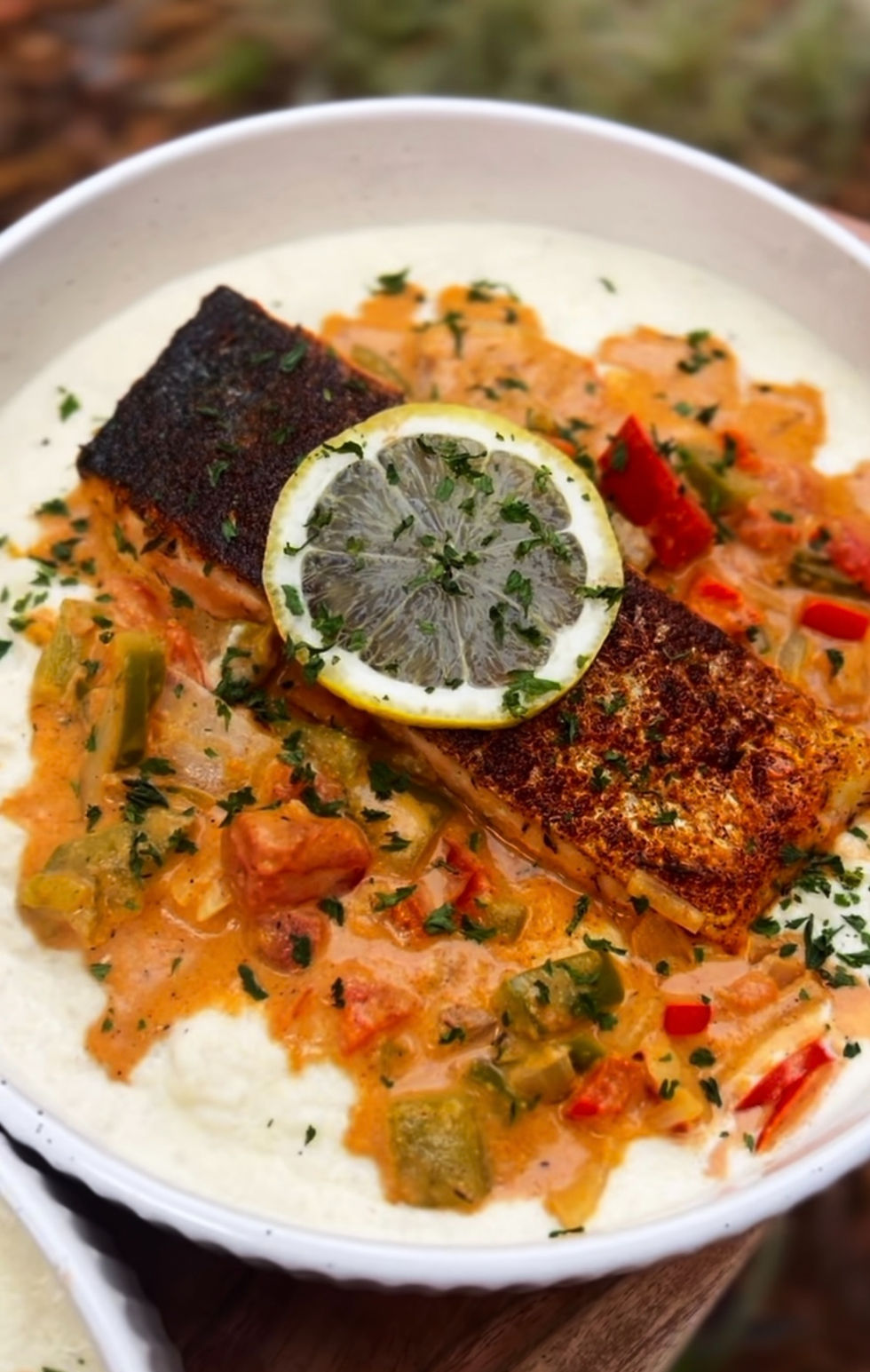 Close-up view of crispy skin Cajun salmon served on a plate with colorful vegetables