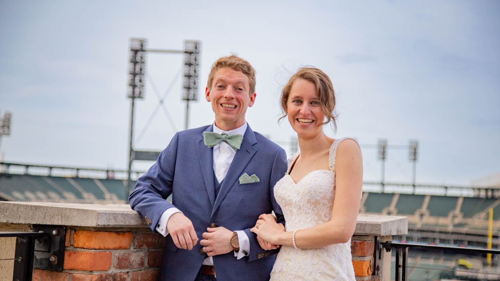 Bride and groom smile with Comerica Park in the background in downtown Detroit