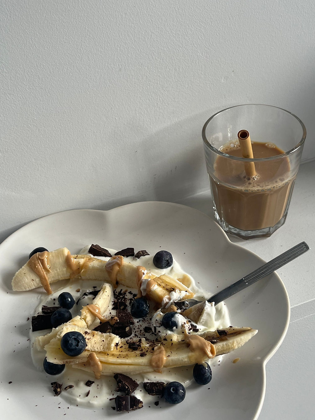 Une banane coupée en 2 disposées sur du yaourt avec des pépites de chcoolat et des myrtilles