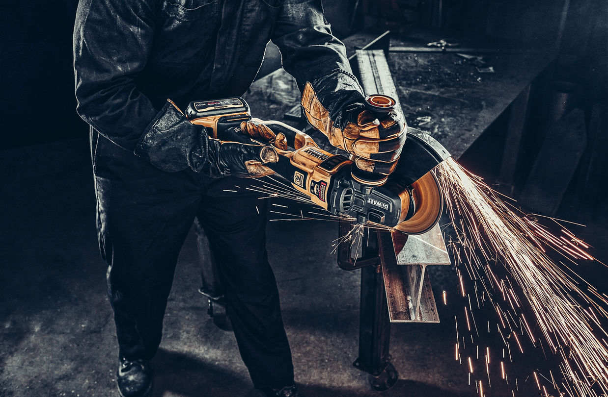 Arbeiter nutzt DEWALT XR FLEXVOLT® Akku-Winkelschleifer zum Trennen von Metall mit starken Funkenflug