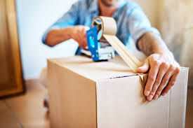 Person taping a cardboard box using packaging supplies