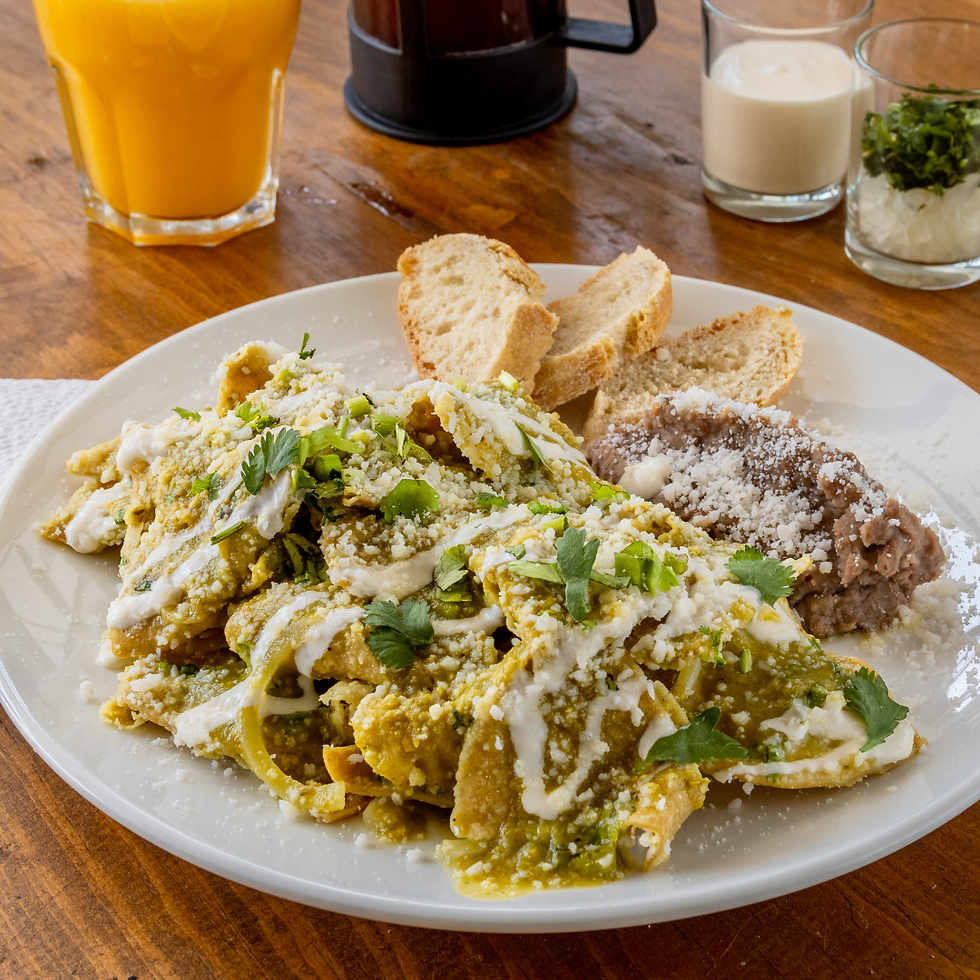 A plate of chilaquiles, drizzled with cream and green onion. Served with refried beans.