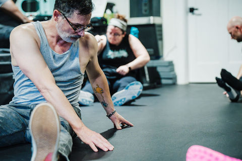 People stretching on a gym floor during a fitness class, group activity