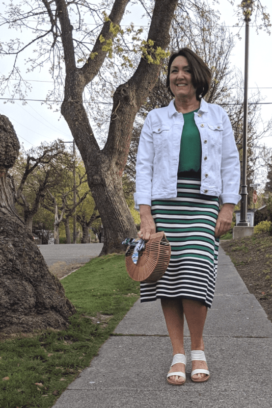A white denim jacket and striped knit skirt outfit looks great with this birdcage shaped purse.