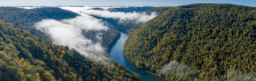 A river winding through lush, green hills in West Virginia, representing West Virginia CPA CPE requirements