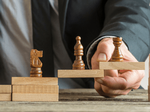 Different chess pieces going up block steps, showing different steps for how to improve your career