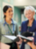 Three healthcare professionals, including a nurse practitioner, stand in a hospital corridor discussing documents, exemplifying team building and effective collaboration as another person walks by in the background.