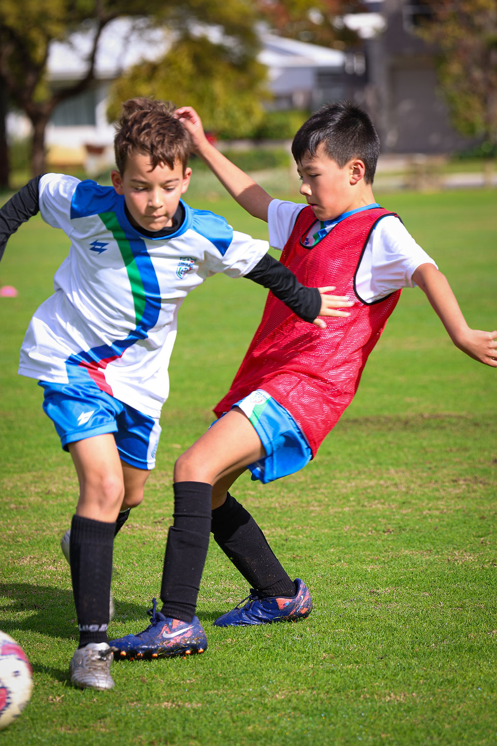 Young footballers demonstrate focus and awareness as they compete for the ball during practice, showcasing essential skills in scanning the field.
