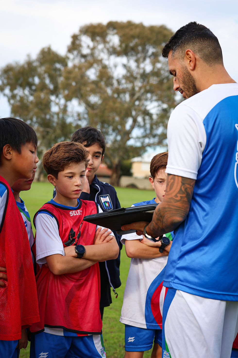 A professional youth soccer coach guiding a young player constructively during a training session