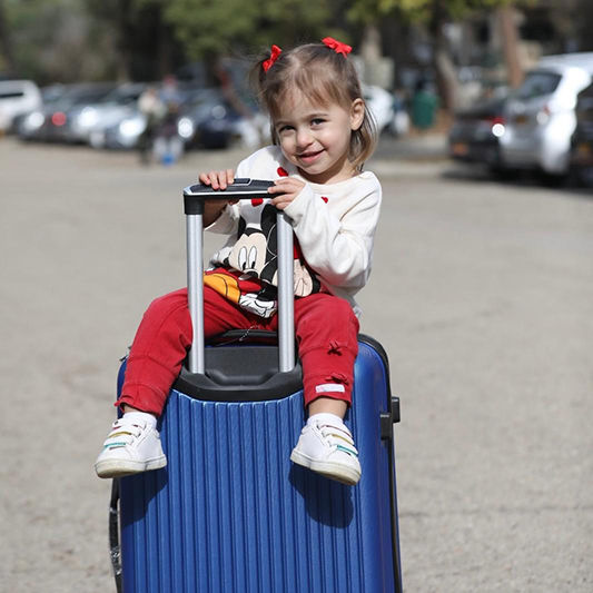 ילדה יושבת על מזוודה