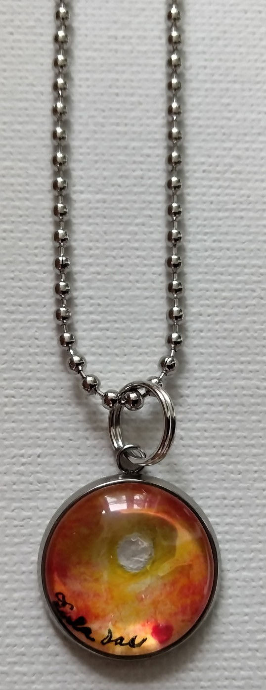 'Radiant Sun' jewelry art piece placed in a circle pendant on a ball chain - the size of a penny