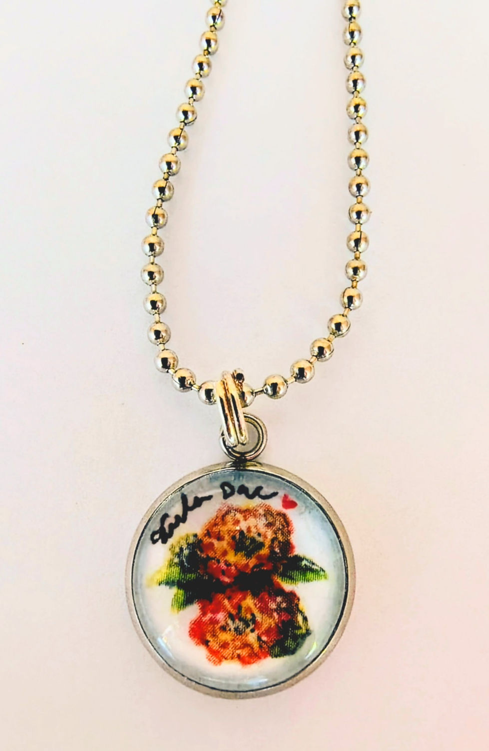 'Lantana' jewelry art piece placed in a circle pendant necklace - art the size of a penny