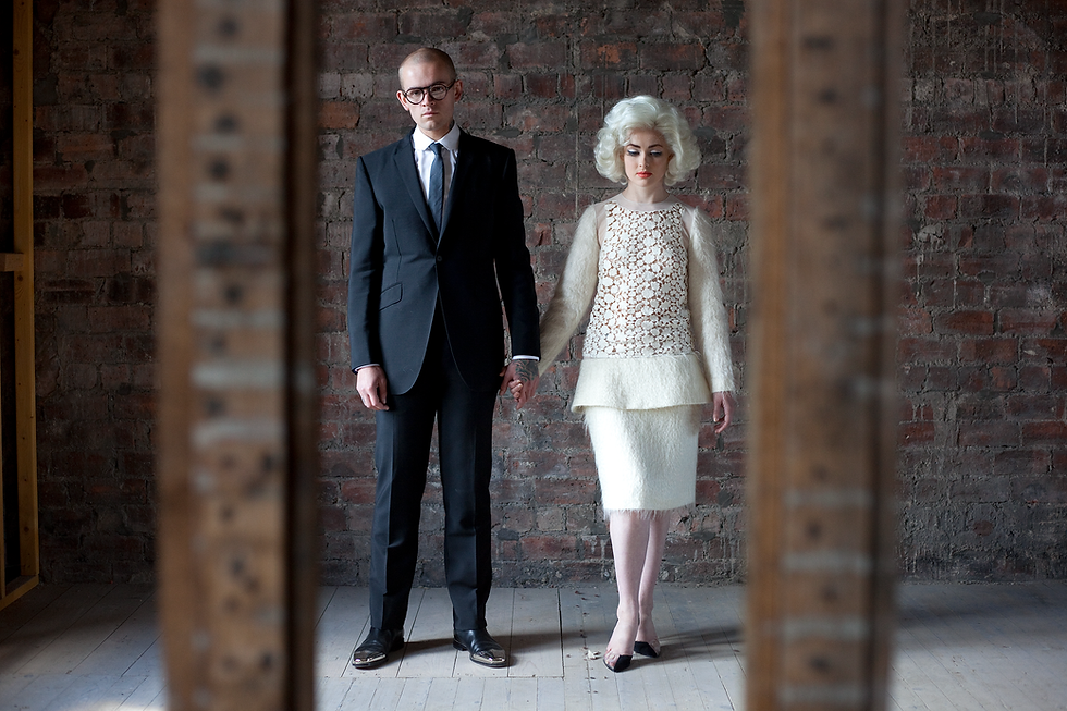 Main and woman dressed up and standing against brick wall from scene in Ruth Paxton's short Nevada