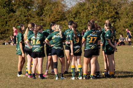 Group of people in green sports uniforms huddling.