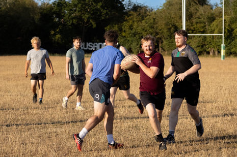 Group playing rugby on a grassy field.