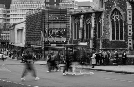 Black and white city scene with blurred pedestrians.