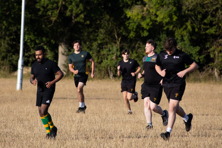Five people jogging in a grassy field.