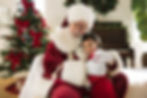 Santa Claus hugging a young girl by a Christmas tree.
