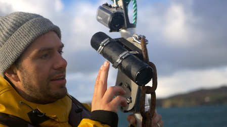Person on a boat inspecting an underwater monitoring camera