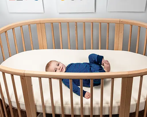 Naturpedic Organic Breathable Oval Crib Mattress for Stokke Sleepi Bed featuring certified organic materials, breathable airflow technology, waterproof protection, non-toxic construction + premium infant sleep support.
