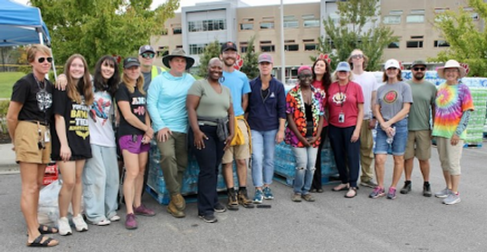 Esther volunteers with many people at a water distribution site 2024.png