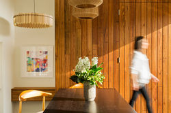 Warm timber-lined dining room with pendant lights, custom cabinetry, flowers and a motion-blurred fi