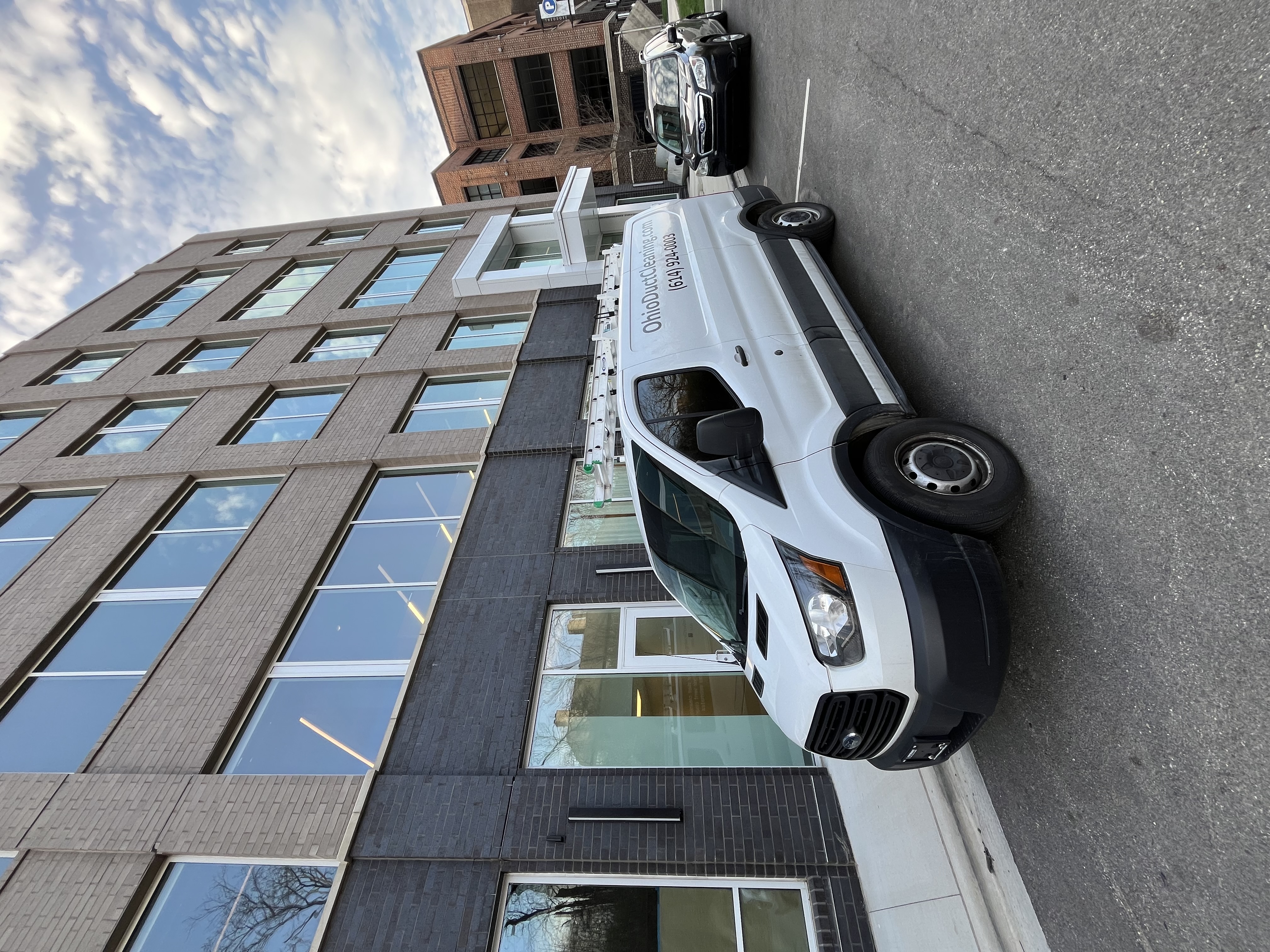Clean Air Pros van at modern Columbus Ohio commercial building — multi-story commercial duct cleaning