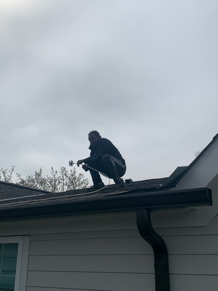 Clean Air Pros technician on roof cleaning a roof-vented dryer vent in Johnstown Ohio condo community