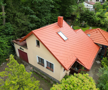 Rodinný dům s červenou střechou obklopený stromy