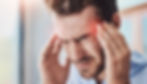 A man presses his temples with both hands, eyes shut in discomfort, showing symptoms of a cervicogenic headache often linked to upper cervical spine misalignment.