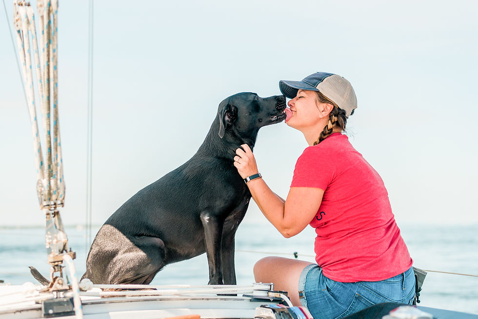 Black lab mix giving owner a kiss as they sit on their boat in the ocean