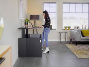 A woman stood using the HomeFit Sit-Stand Desk at home