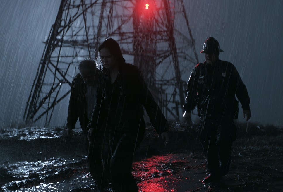 Three figures in heavy rain beneath a tower's red light.