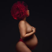 femme enceinte de profil dénudée avec une grosse fleur rouge sur les cheveux