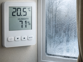 Thermostat intérieur affichant un taux d’humidité élevé avec condensation visible sur une fenêtre en hiver