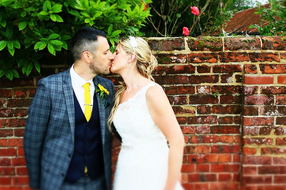 Bride and Groom kissing in front of a brick wall, Elm Farm, Norfolk