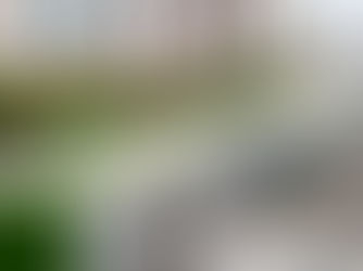 Vue aérienne de la station de VLT Mucuripe à Fortaleza, montrant un train moderne à quai devant une station au toit vert, avec les immeubles de la ville en arrière-plan.