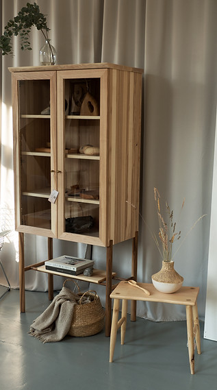 Schrank aus Esche mit Nussbeinen und Glastüren, gefüllt mit Holzk Unikaten neben einem Hocker aus Ahorn